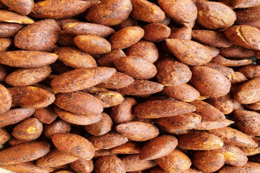 Amandes entières nature disposées en tas sur une surface en bois rustique, capturant leur texture croquante et leur teinte brun doré naturelle.
